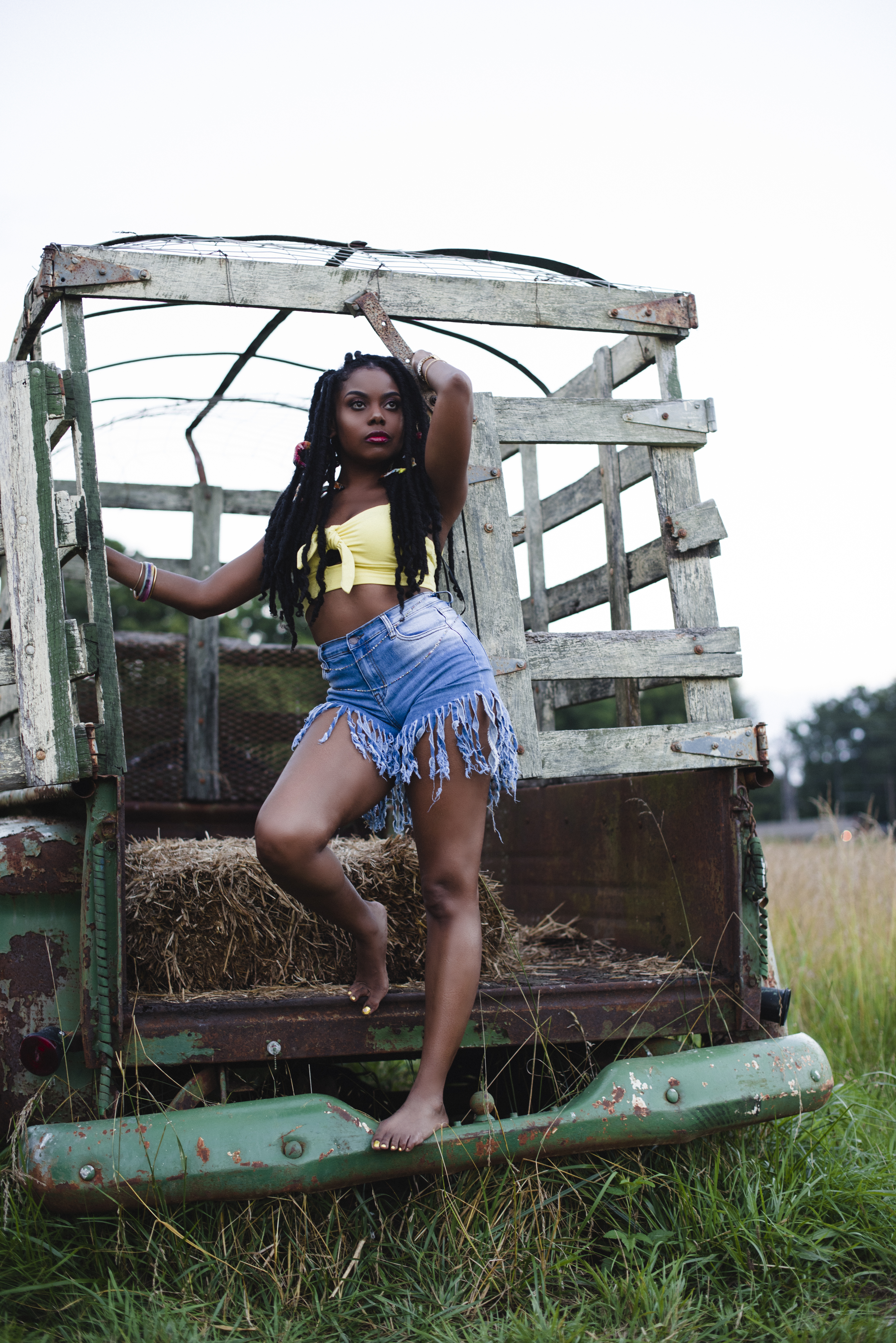 Standing on the bumper of a vintage truck in a hay field