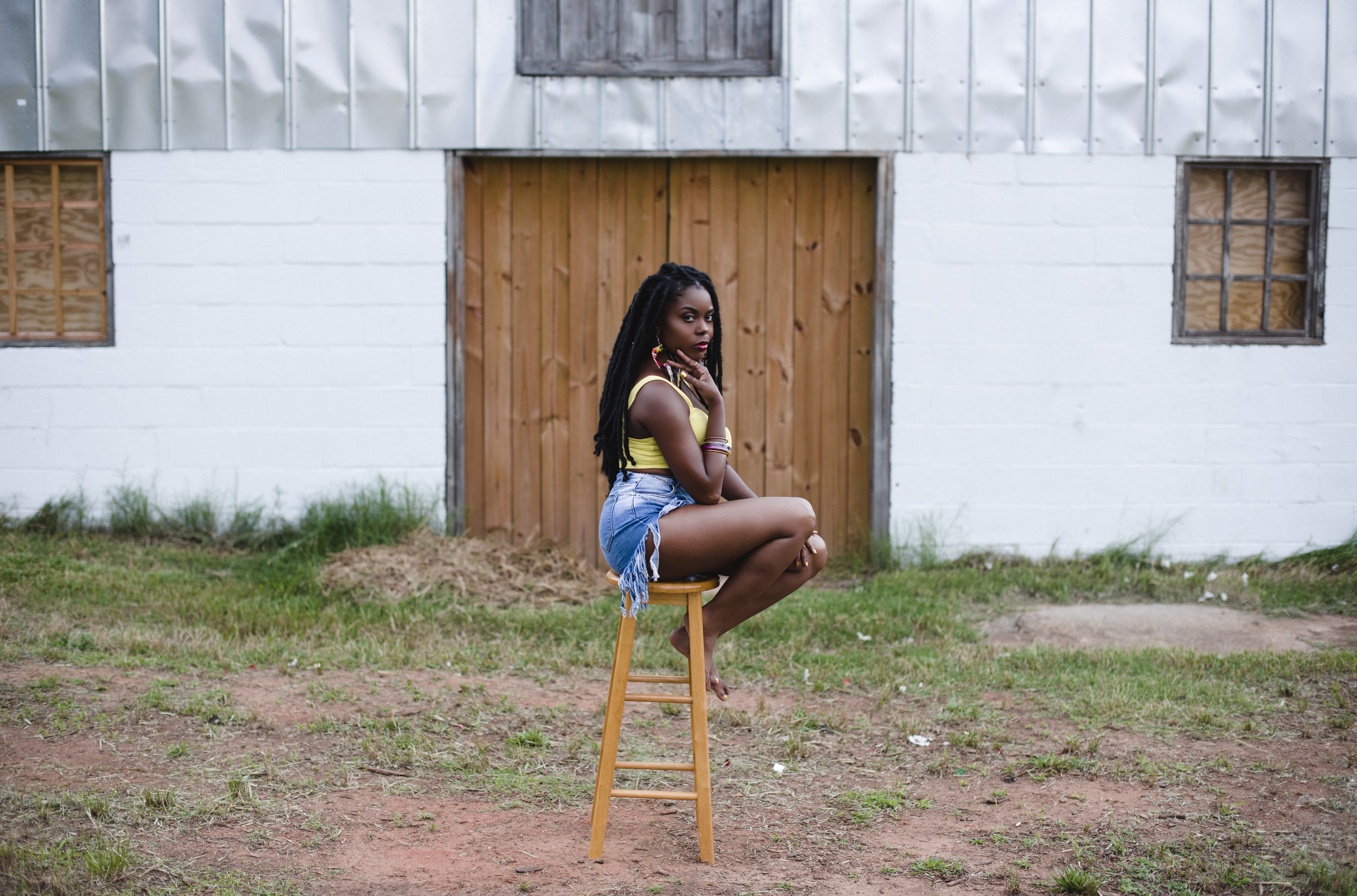 Sitting on a wooden stool in front of a rustic barn