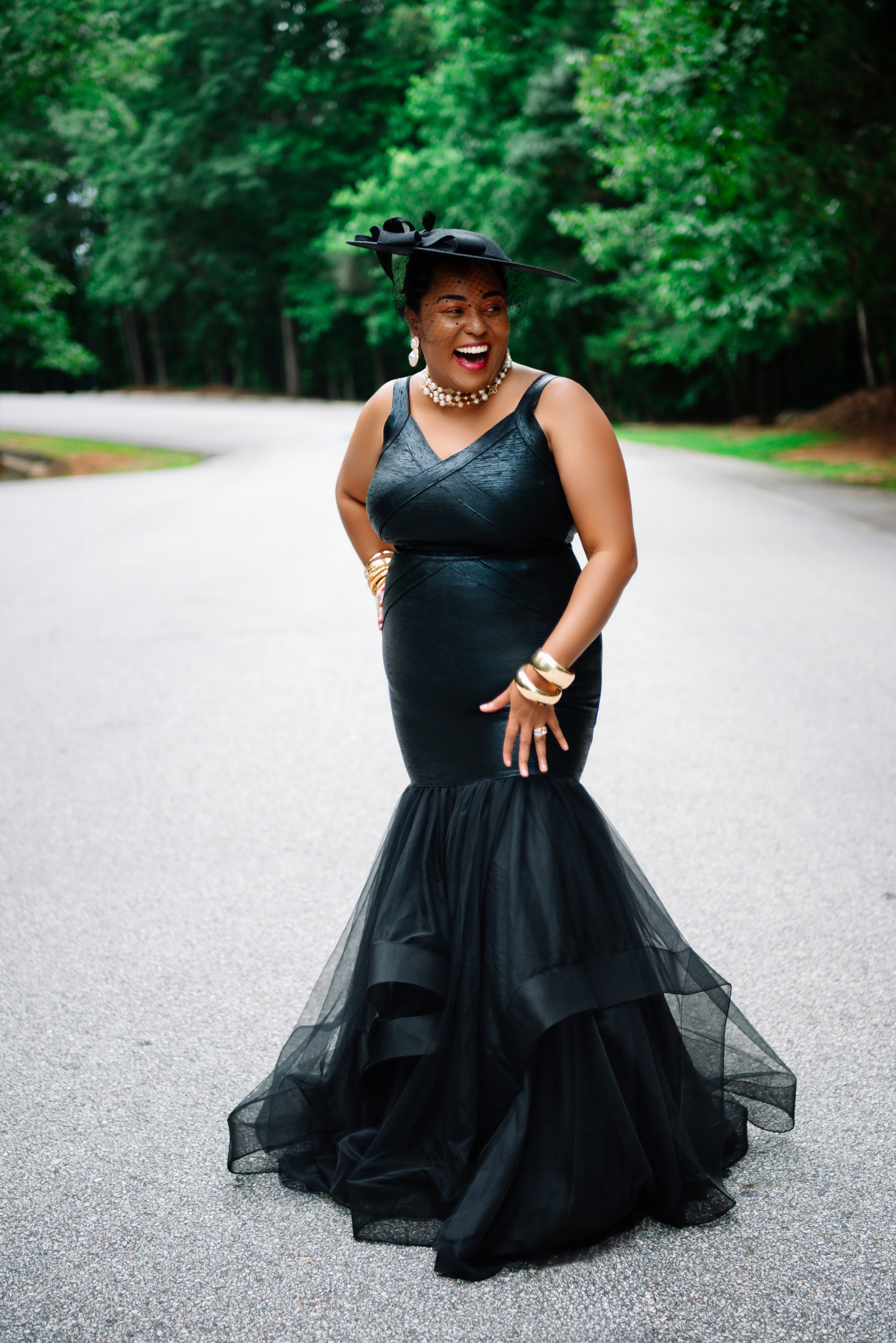 Laughing in a black dress with a layered tulle skirt, hands near her waist