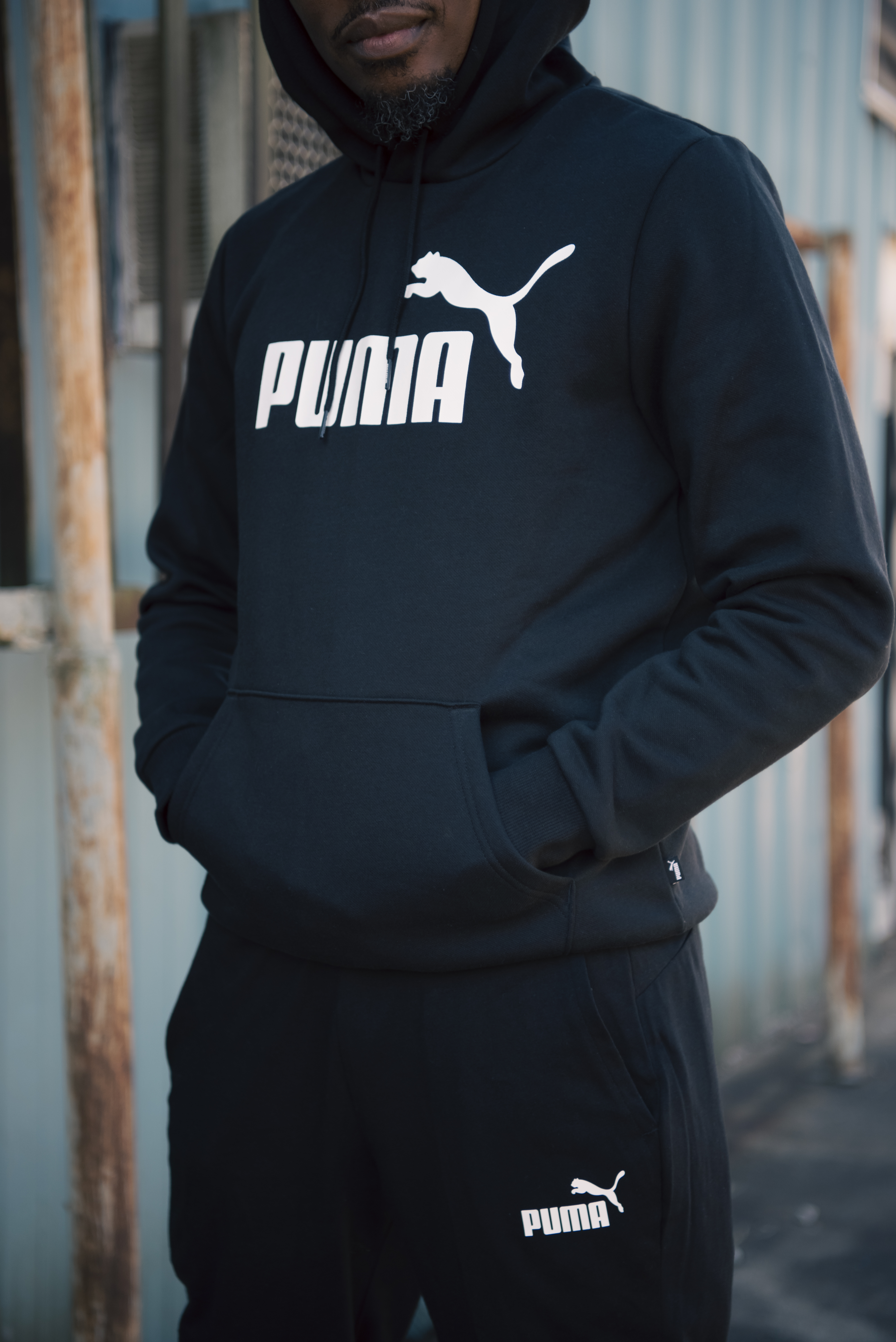 Close-up of a black Puma hoodie with the large logo, hands in the pocket